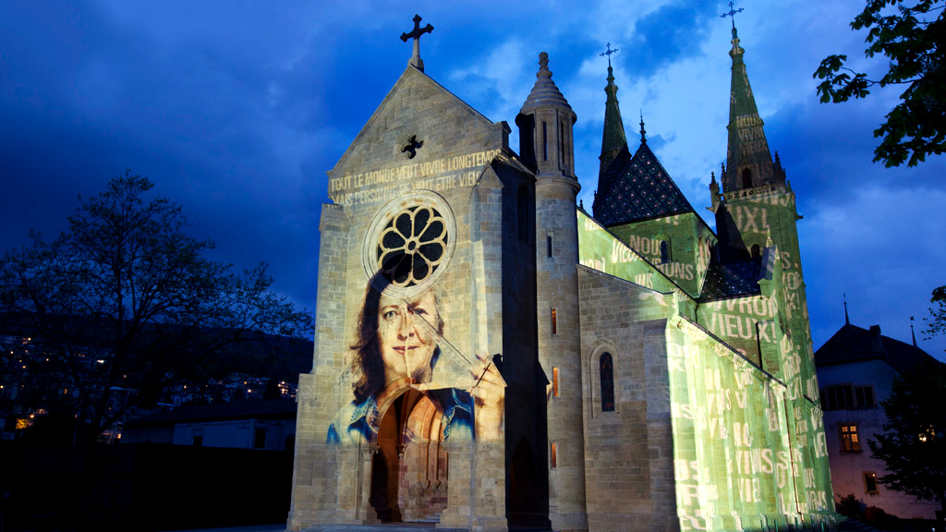 Vom Lichtkünstler Gerry Hofstetter beleuchtete Stiftskirche in Neuenburg zum Thema Hochaltrigkeit