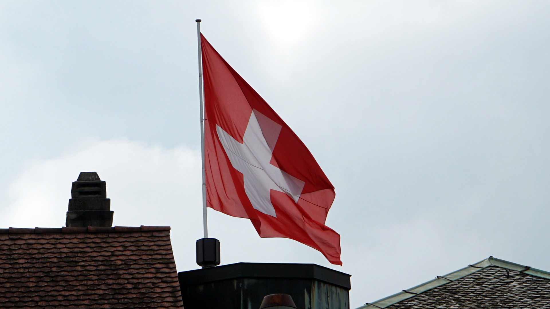 Schweizer Fahne über Hausdächern