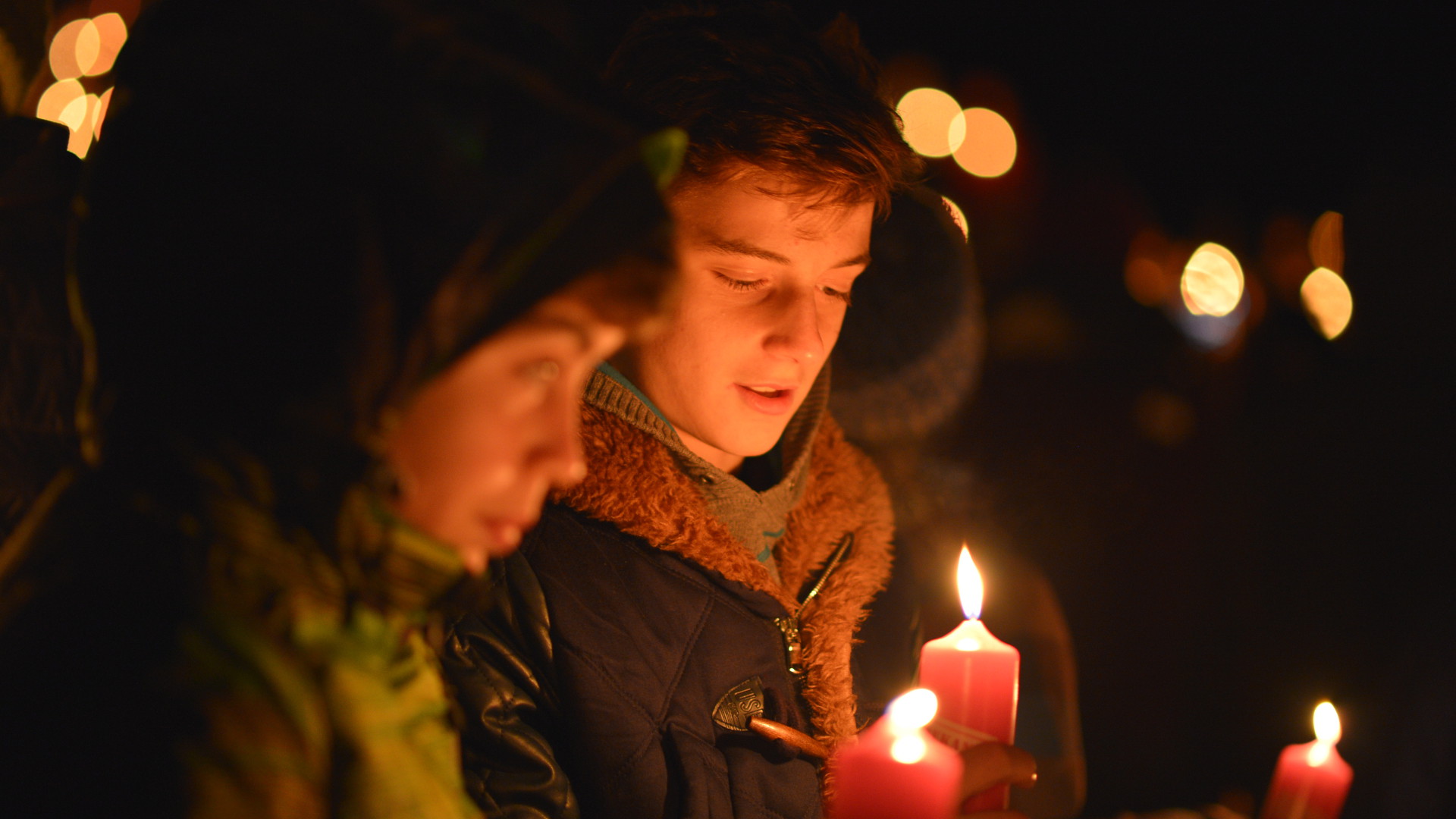 Jugendliche halten Kerzen mit dem Friedenslicht aus Bethlehem