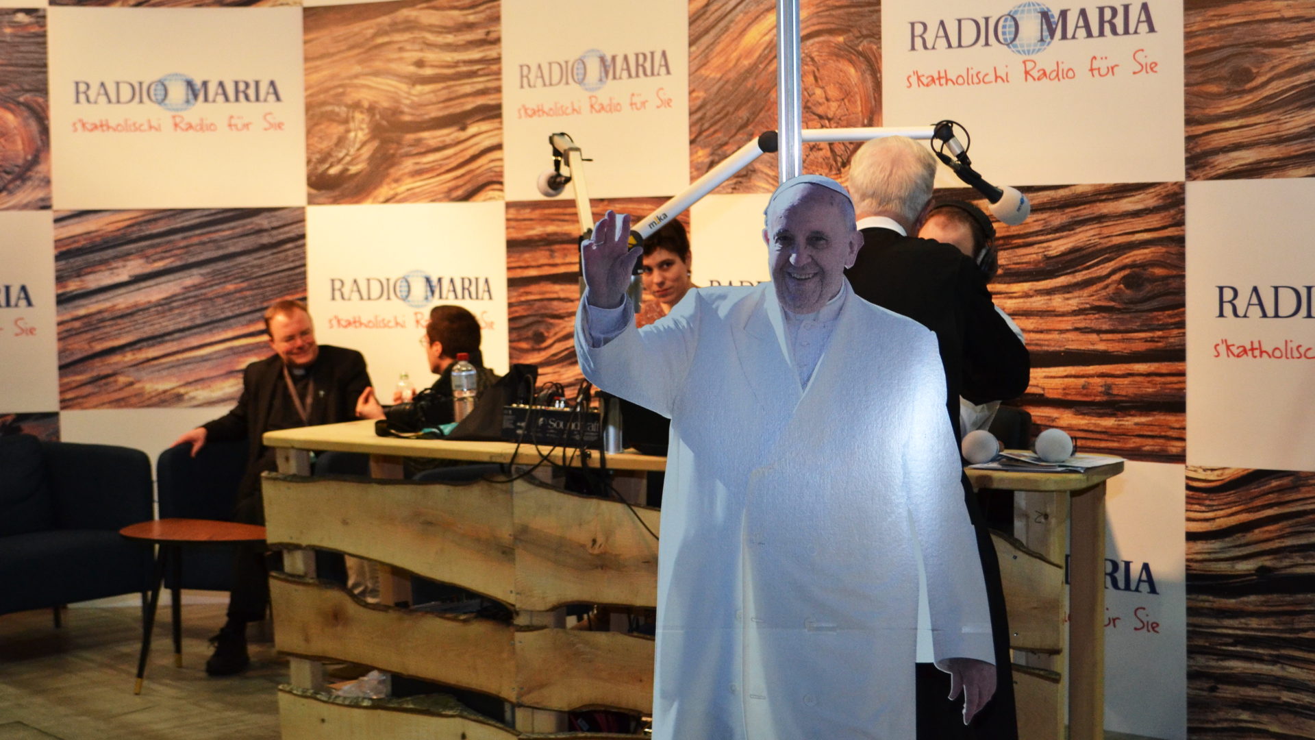 Papst Franziskus aus Pappkarton am Stand von Radio Maria – links im Hintergrund ist Pfarrer Rellstab.