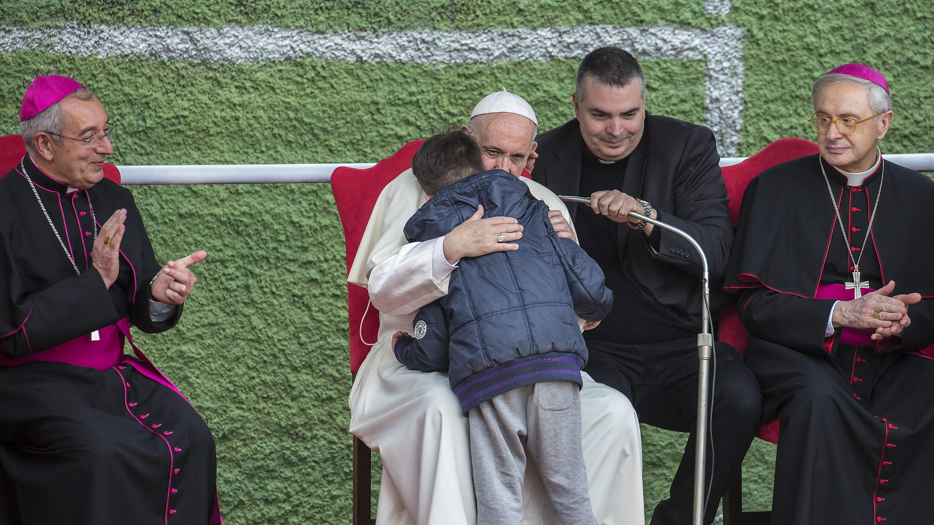Papst Franziskus umarmt einen Jungen.