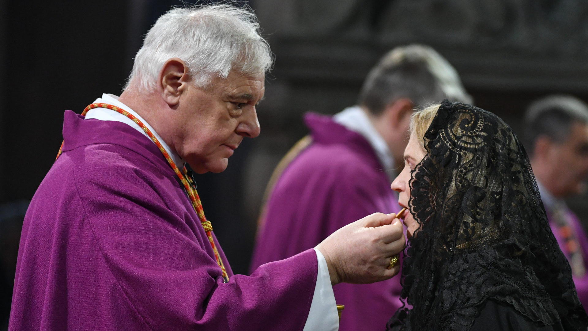 Kardinal Gerhard Ludwig Müller spendet einer Dame des Ritterordens die Mundkommunion