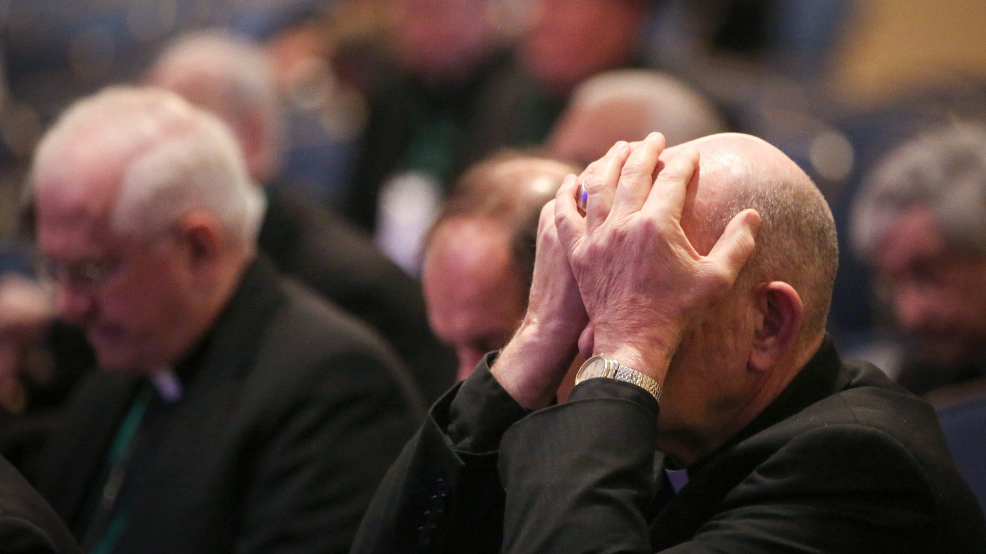 Ein Teilnehmer der Herbstvollversammlung der US-Bischofskonferenz am 12. November in Baltimore hält die Hände vor's Gesicht