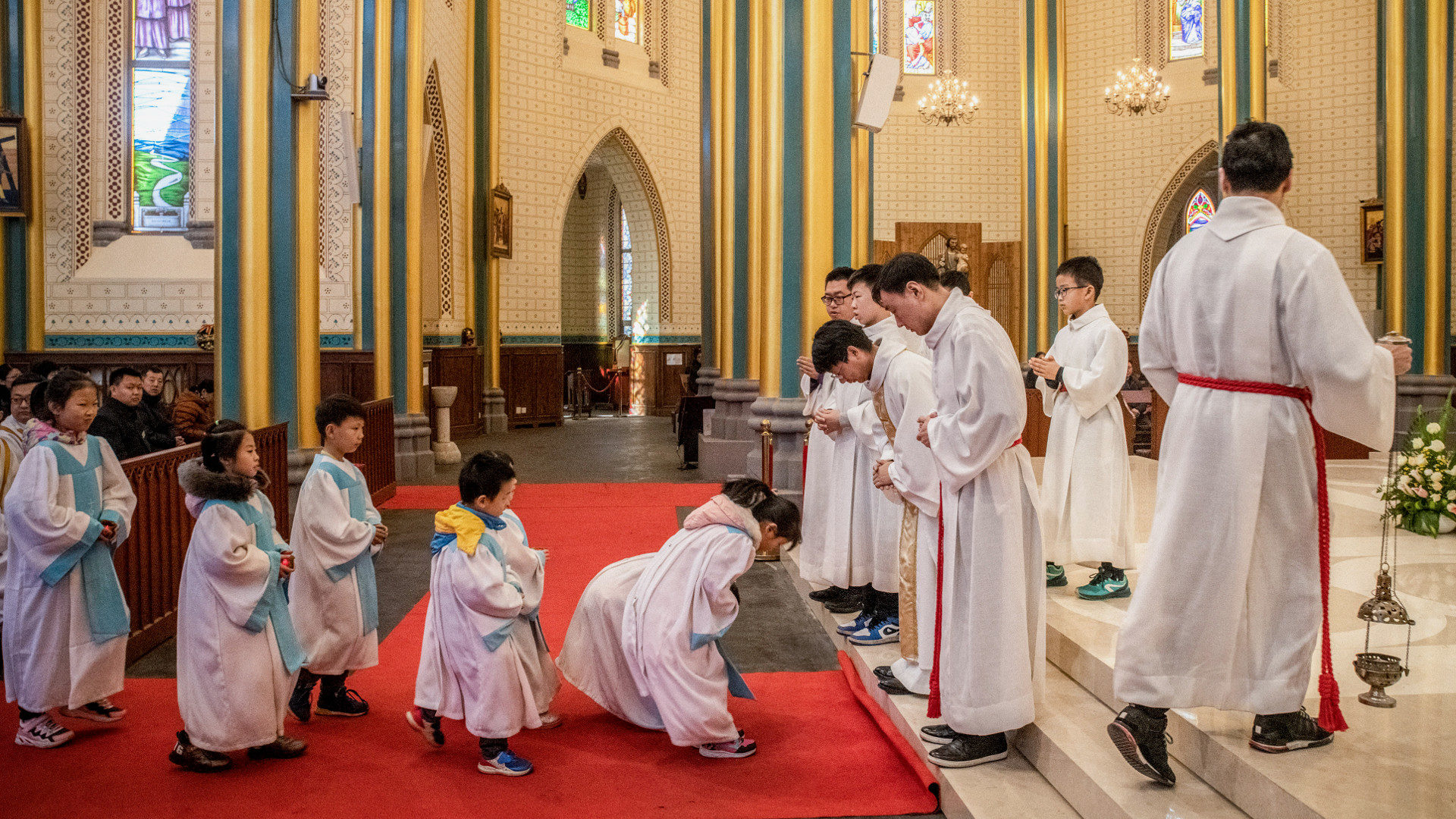 Kinder verbeugen sich vor dem Priester während einer Messe  in Peking.