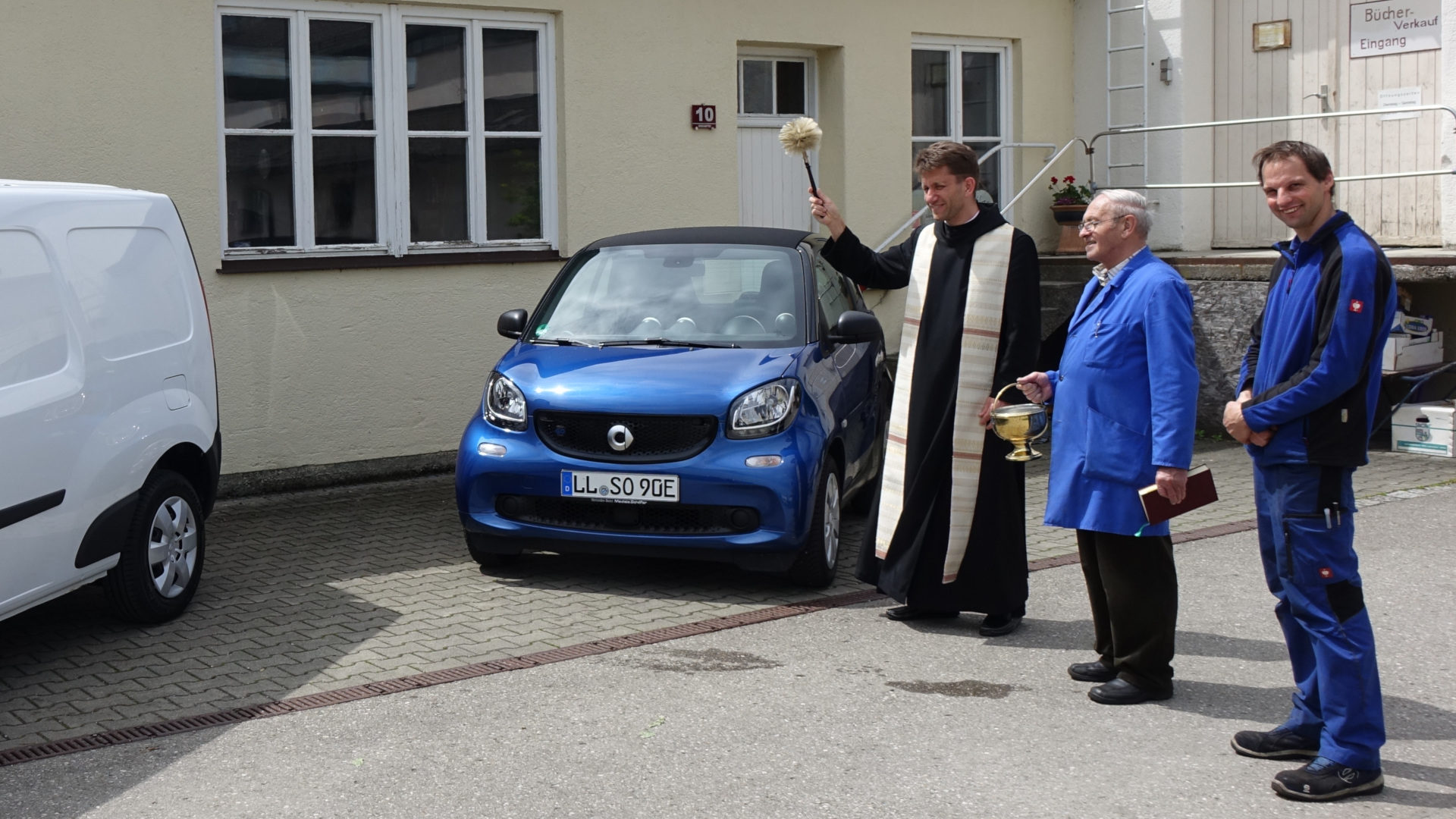Segnung der neuen Elektroautos von St. Ottilien durch Pater Timotheus, daneben Automechaniker