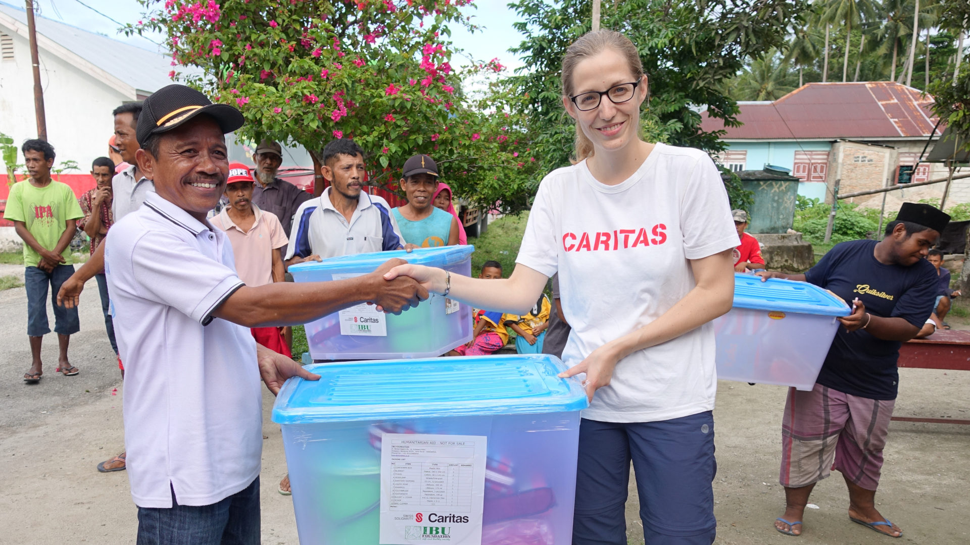 Nach der Katastrophe in Indonesien: Ein Mann im Dorf Lombongga nimmt von Caritas-Mitarbeiterin Patricia Kröll das Nothilfepaket für seine Familie entgegen