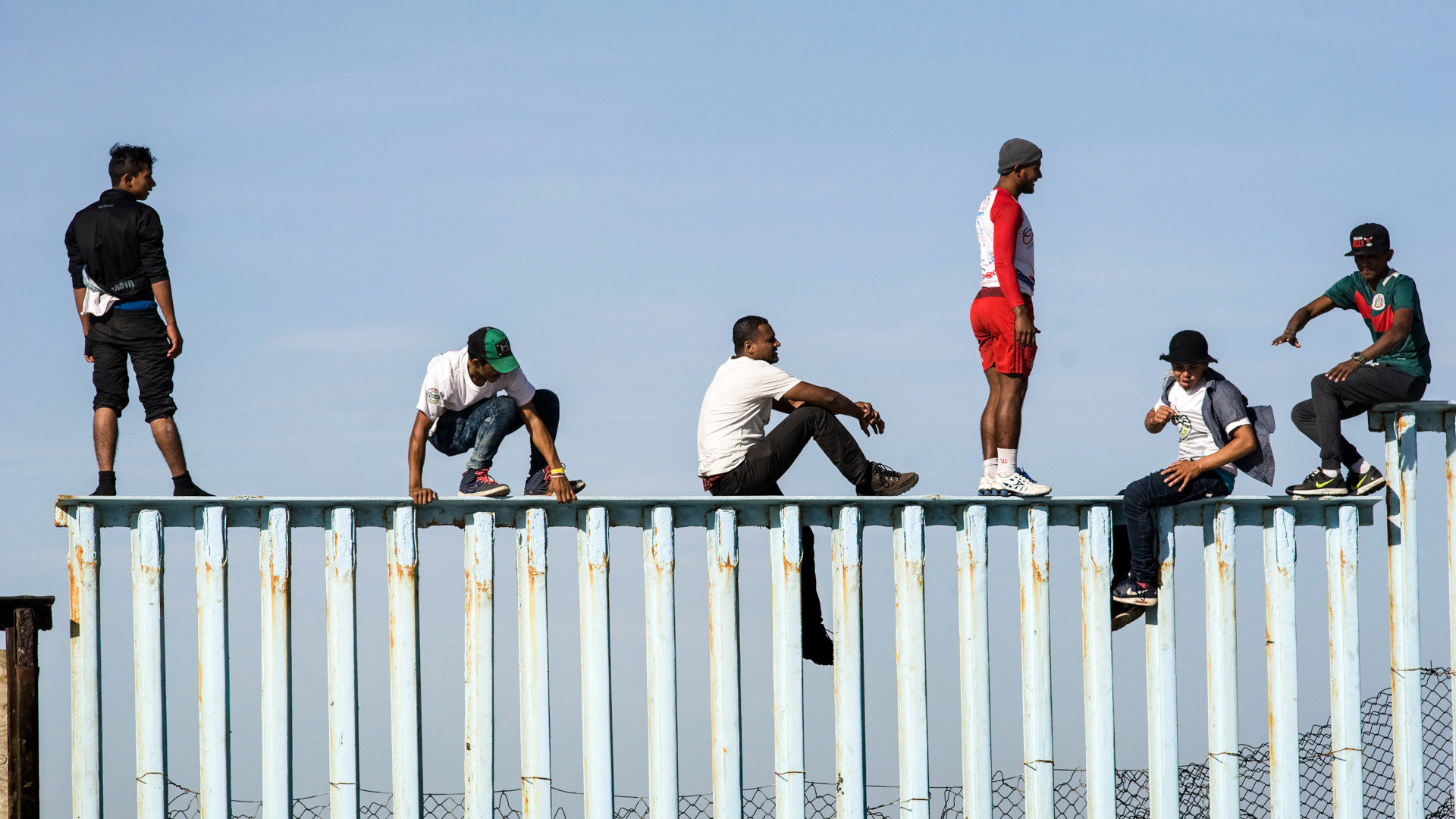 Männer aus Mittelamerika auf dem Grenzzaun zwischen Mexiko und den USA in Tijuana.