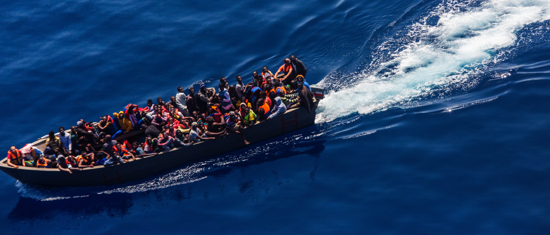 Ein Holzboot mit Flüchtlingen in Seenot auf dem Mittelmeer.