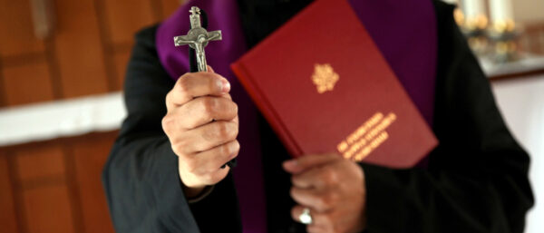 Priester mit Kreuz und Exorzismusbuch | KNA