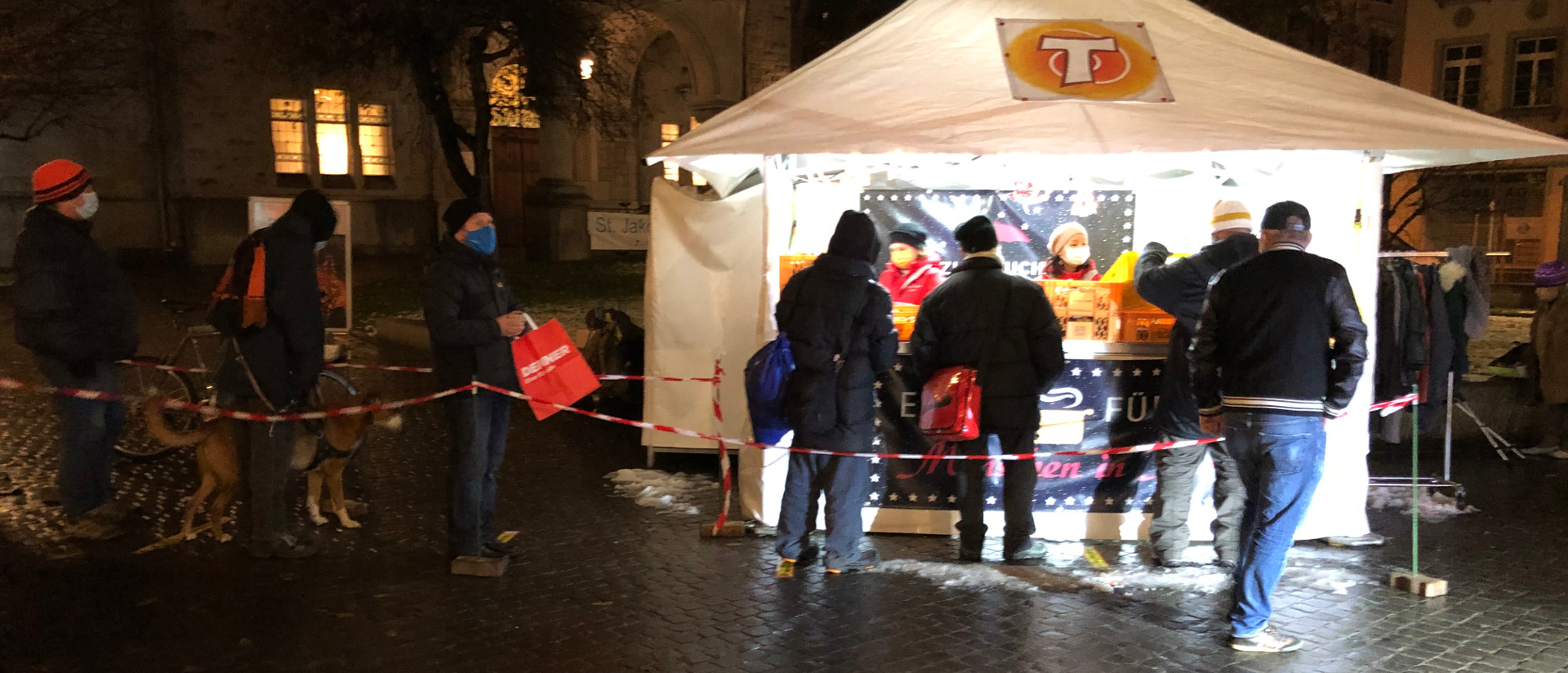 Die Menschen stehen Schlange für eine warme Mahlzeit offeriert von der Franziskanischen Gassenarbeit.