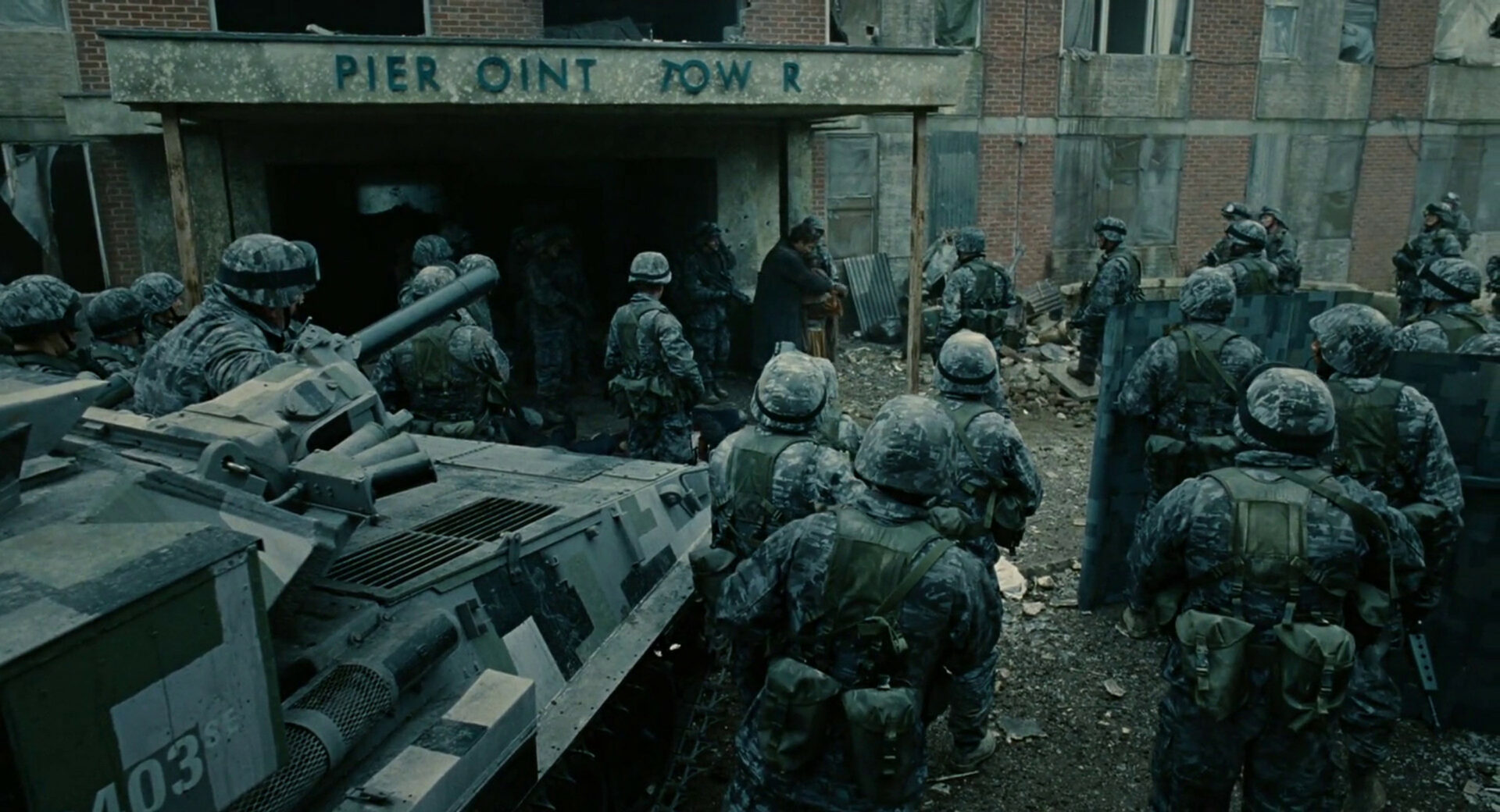 Theo (Clive Owen) bringt Kee (Claire-Hope Ashitey) und das Baby aus dem Haus. Die Soldaten stellen vor lauter Überraschung das Feuer ein. Screenshot.