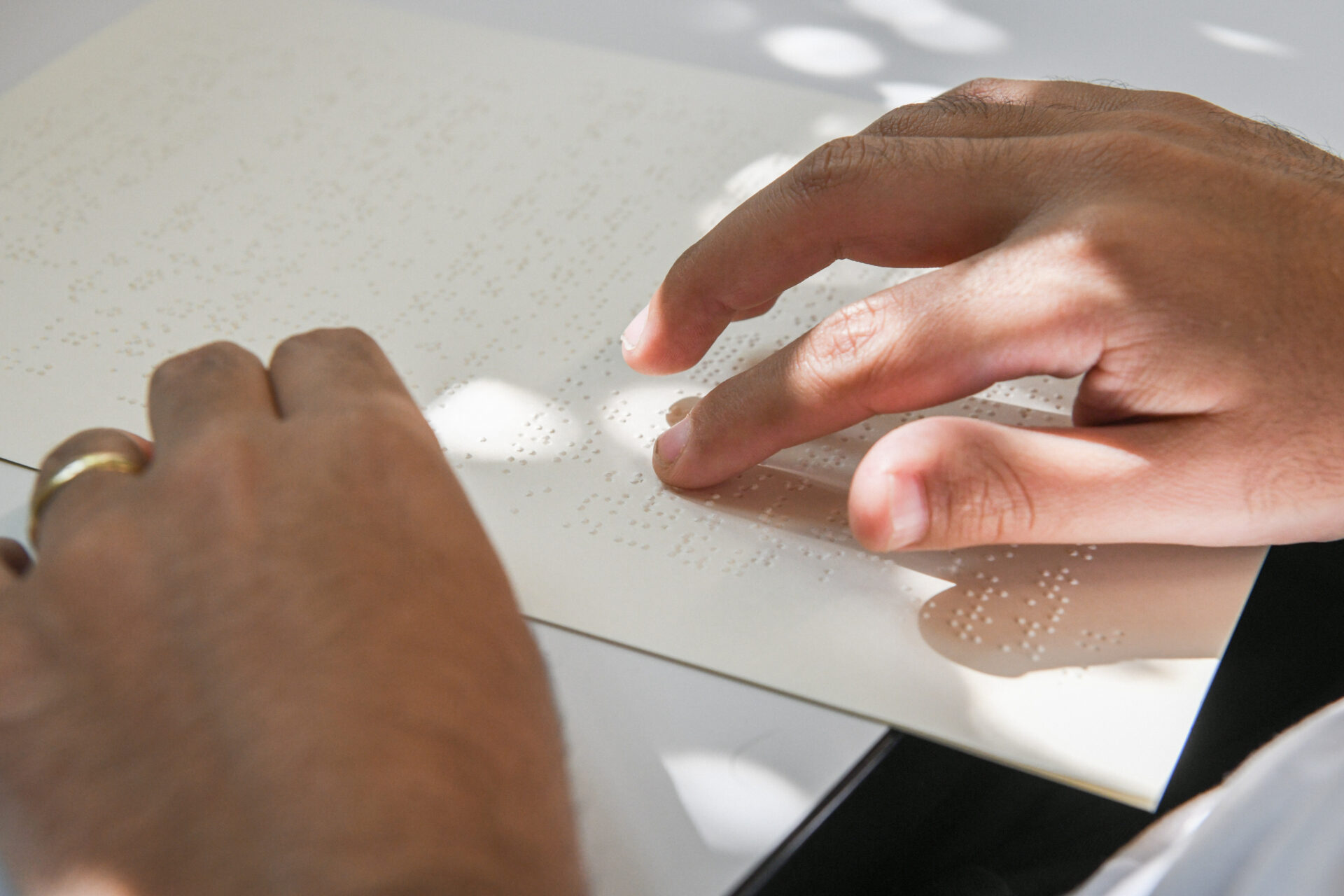 Ein blinder Mann liest mit Hilfe seiner Fingerkuppen eine Seite in Braille-Schrift.