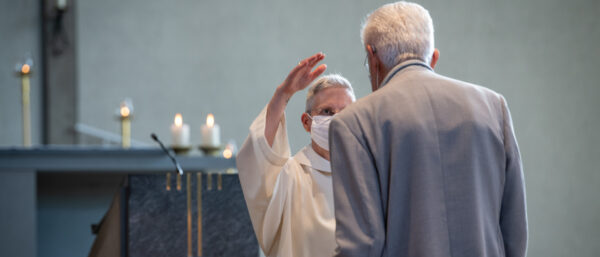 Gemeindeleiterin Dorothee Becker segnet einen Mann in der Kirche St. Franziskus in Riehen BS. | Manuela Matt
