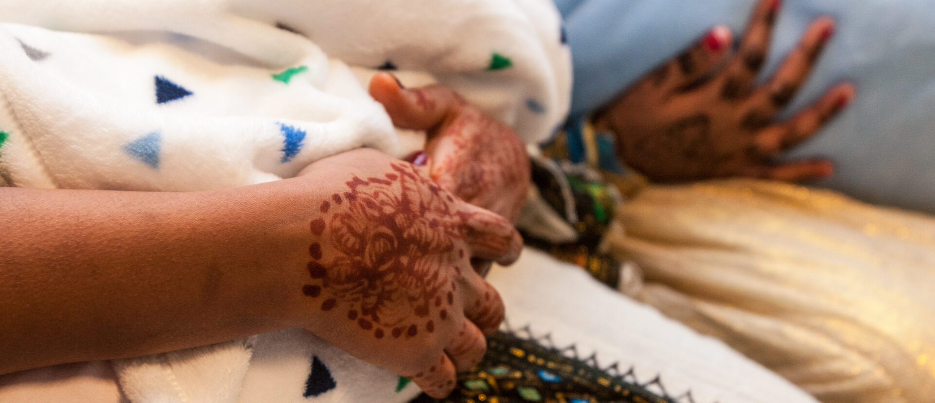 Frauen aus einer eritreisch-orthodoxen Gemeinde halten ihre in Tücher gewickelten Säuglinge in den Armen. Sie sind traditionell gekleidet und haben mit Ornamenten verzierte Hände.
