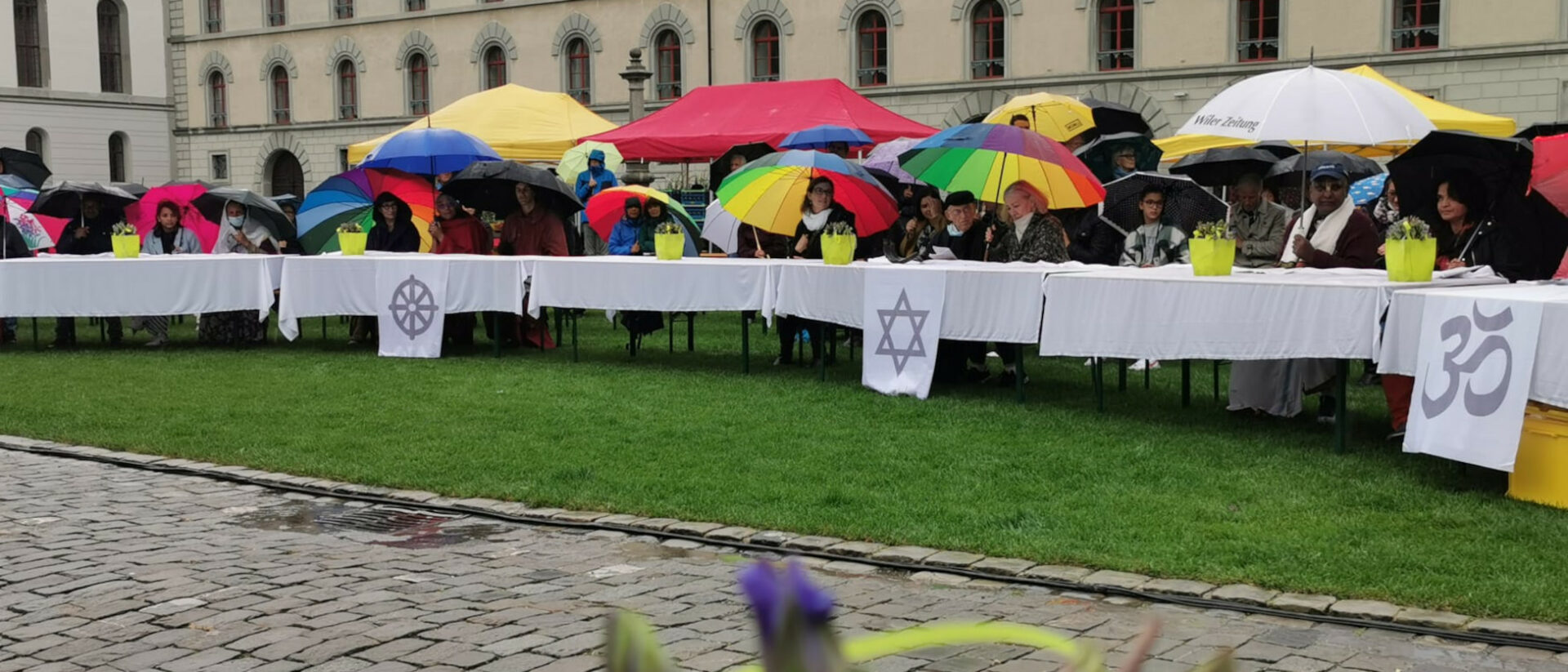 Unter bunten Schirmen: Mitfeiernde der interreligiösen Bettagsfeier im Kreis der Religionen