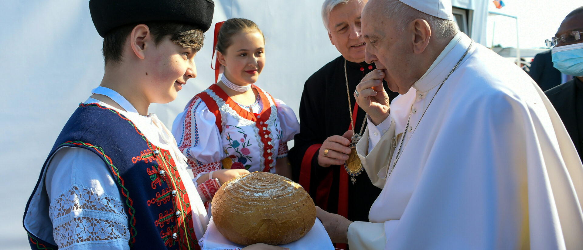 Ein Jugendlicher in traditioneller Kleidung reicht Papst Franziskus ein Laib Brot vor dem Sportstadion in Presov (Slowakei).