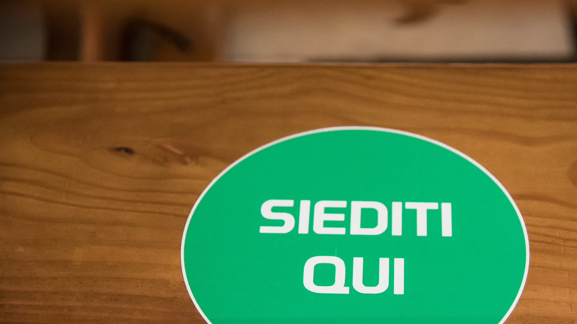 "Setzen Sie sich hier": Aufkleber auf einer Kirchenbank.