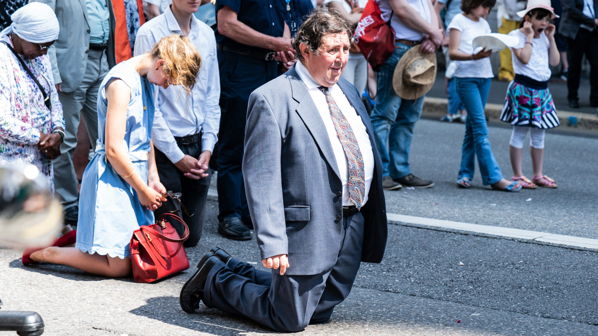 Mann kniet auf der Strasse vor der Kathedrale beim Segen durch den Bischof.