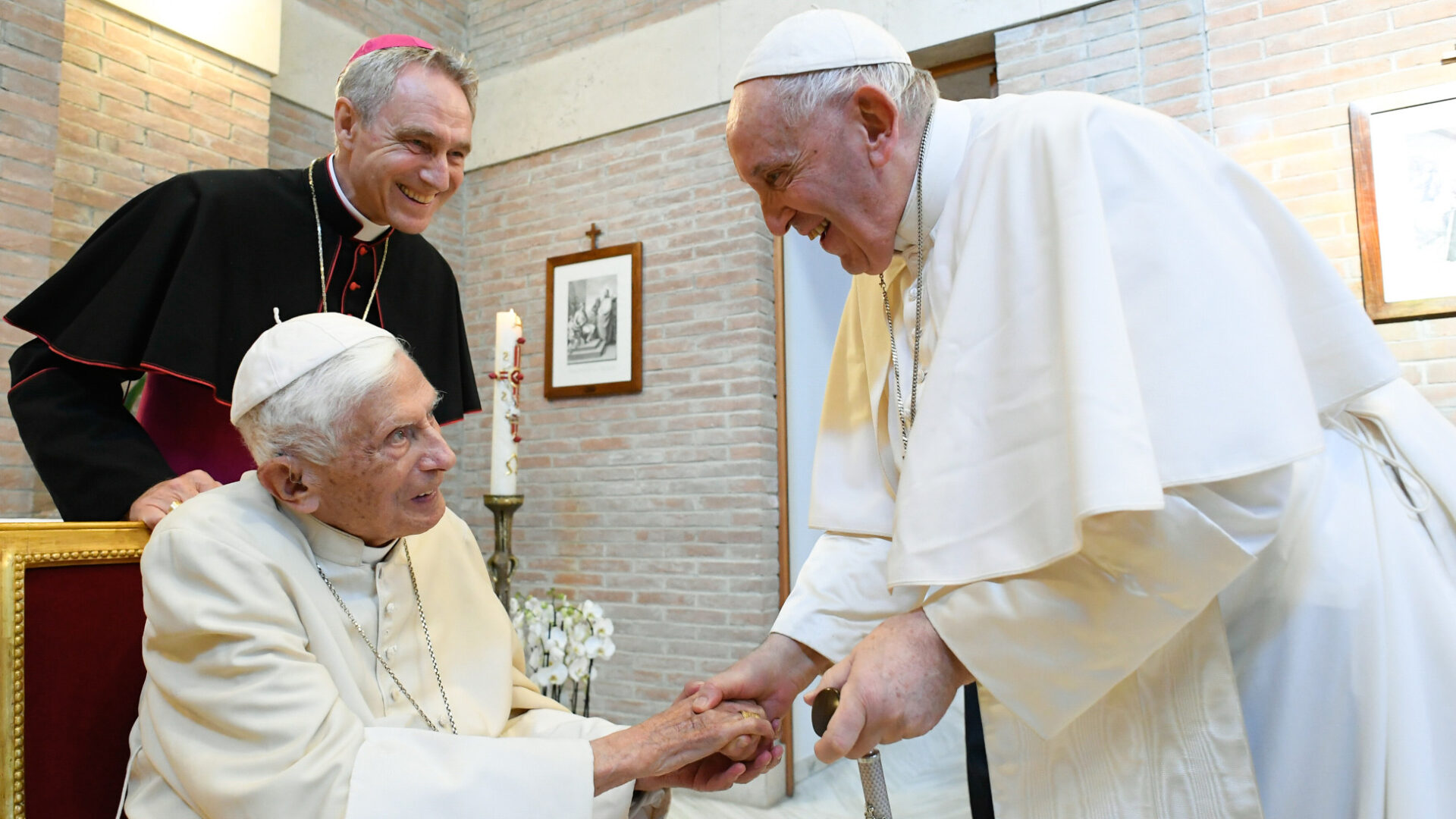 Der emeritierte Papst Benedikt XVI. (l.) begrüsst Papst Franziskus 2022, dahinter Erzbischof Georg Gänswein. | KNA