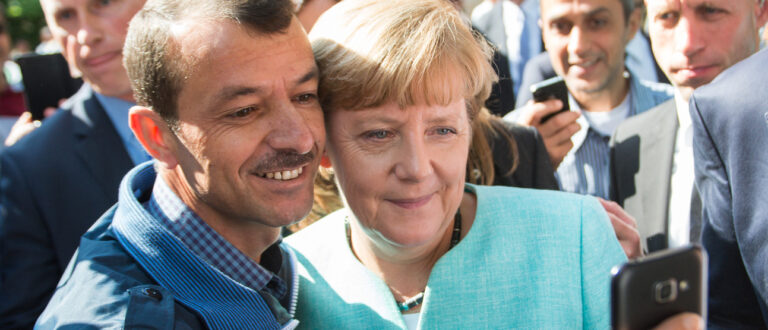 Angela Merkel 2015 mit einem Flüchtling | Keystone