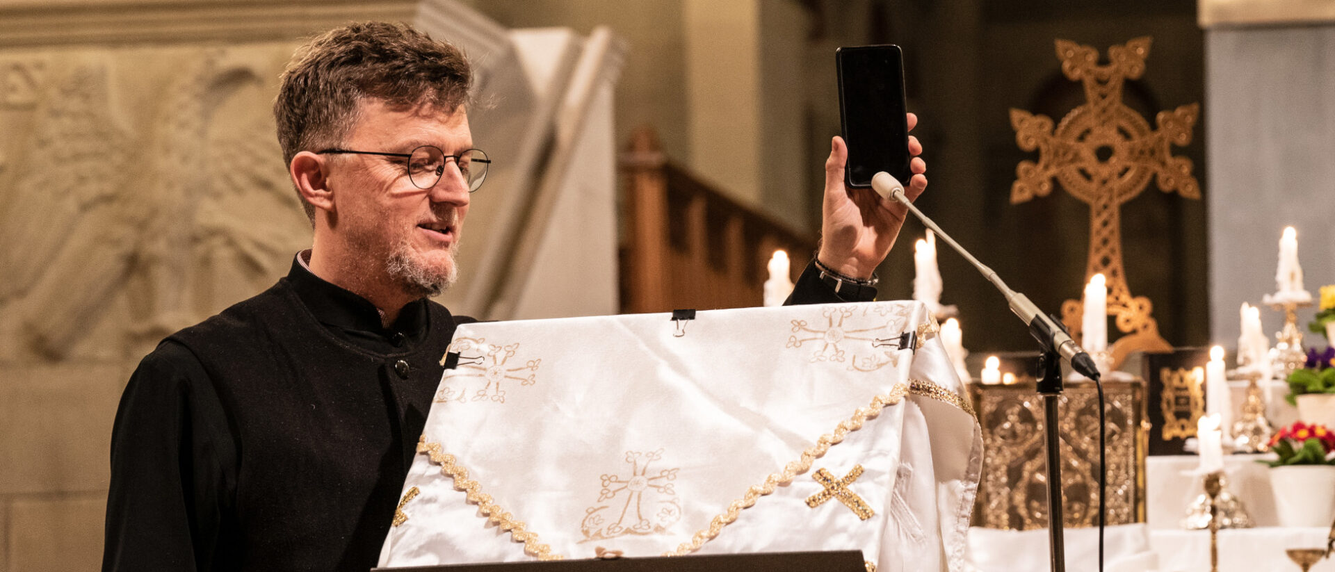 Diakon Dani Schärer hält das Handy ans Mikrophon, damit die Gläubigen die Predigt des abwesenden Erzpriesters Stefanos Athanasiou hören können.