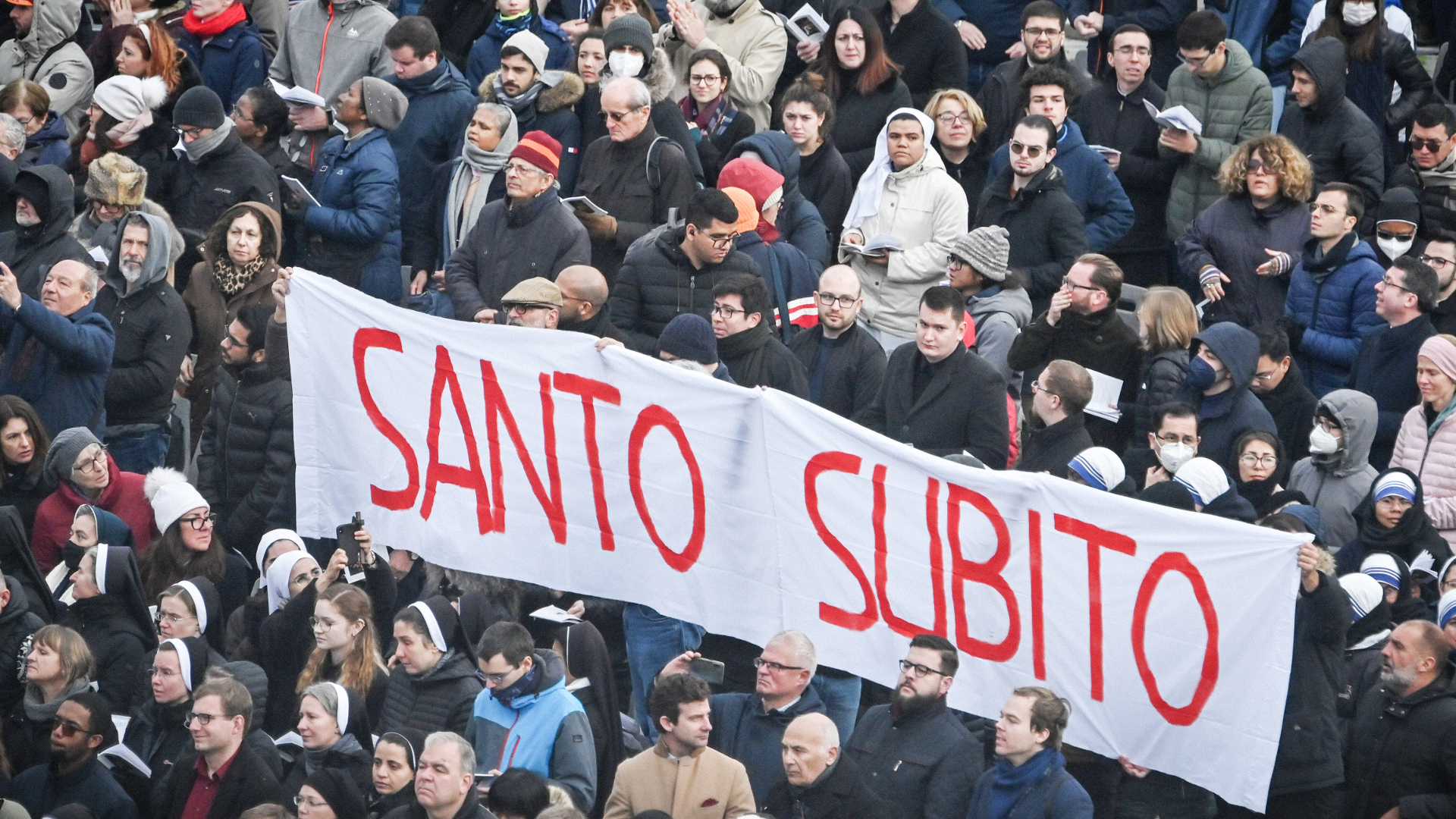 Gläubige halten ein Banner mit der Aufschrift "Santo Subito"  bei der Trauermesse für Benedikt XVI., Januar 2023