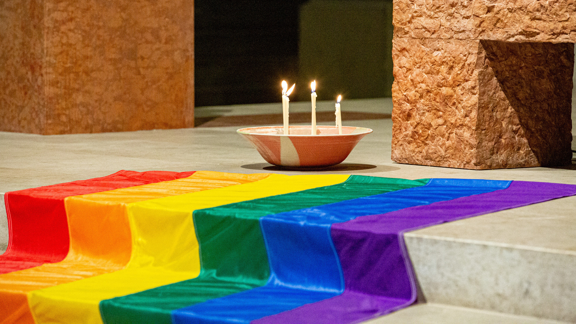 Vier brennende Kerzen in einer Schale auf den Altarstufen zum 20-jährigen Bestehen von Queer-Gottesdiensten in München.