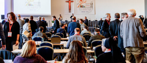 Teilnehmerinnen und Teilnehmer unterhalten sich im Sitzungssaal in Prag. | Björn Steinz/KNA