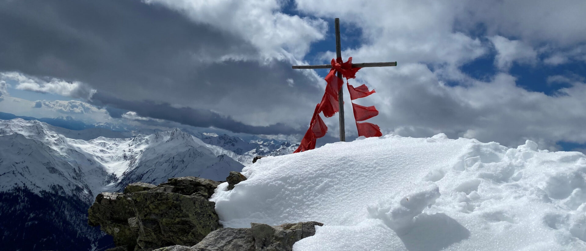 Südtirol meets Tibet: Gipfelkreuz und tibetische Gebetsfahnen in den Alpen.