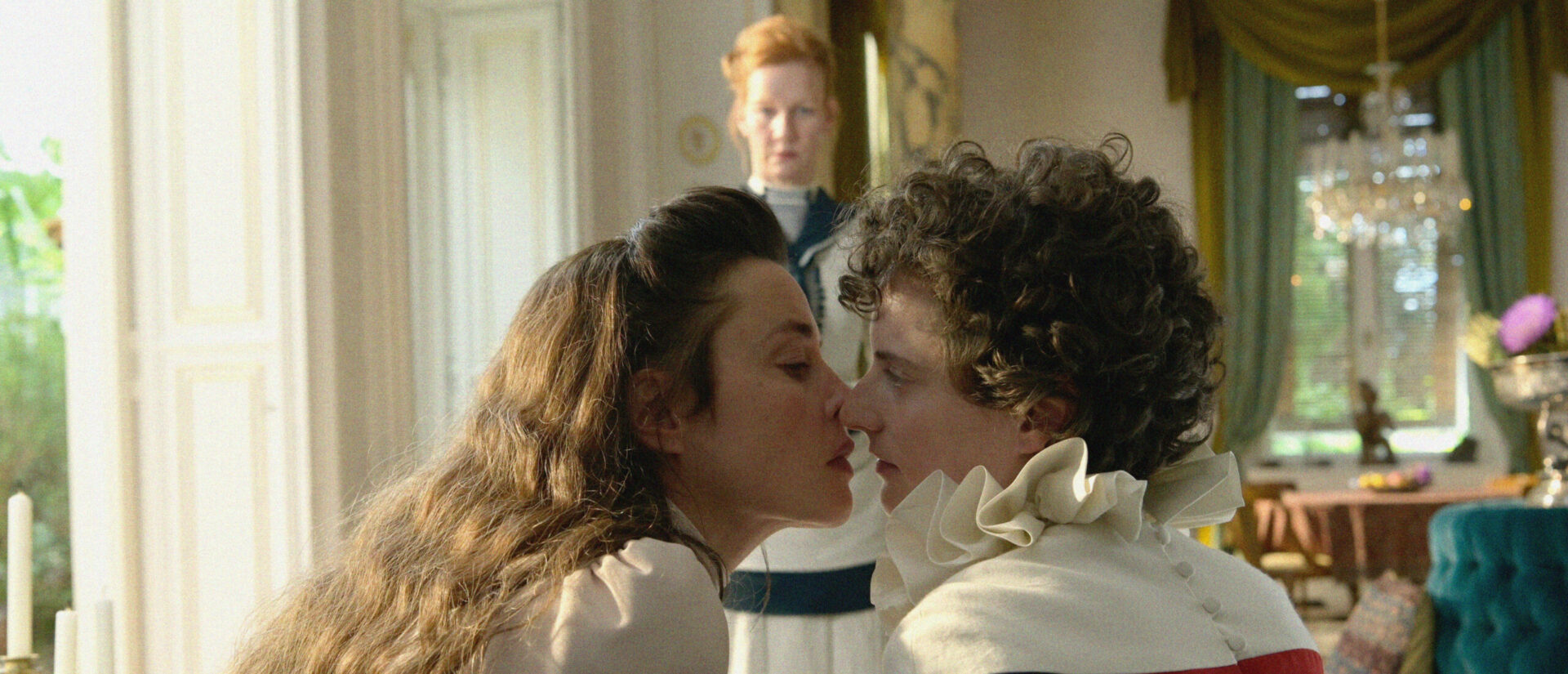Sis (Susanne Wolff, li.) küsst ihre queere Zofe Fritzi (Sophie Hutter) zum Entsetzen von Hofdame Irma (Sandra Hüller, Hintergrund).