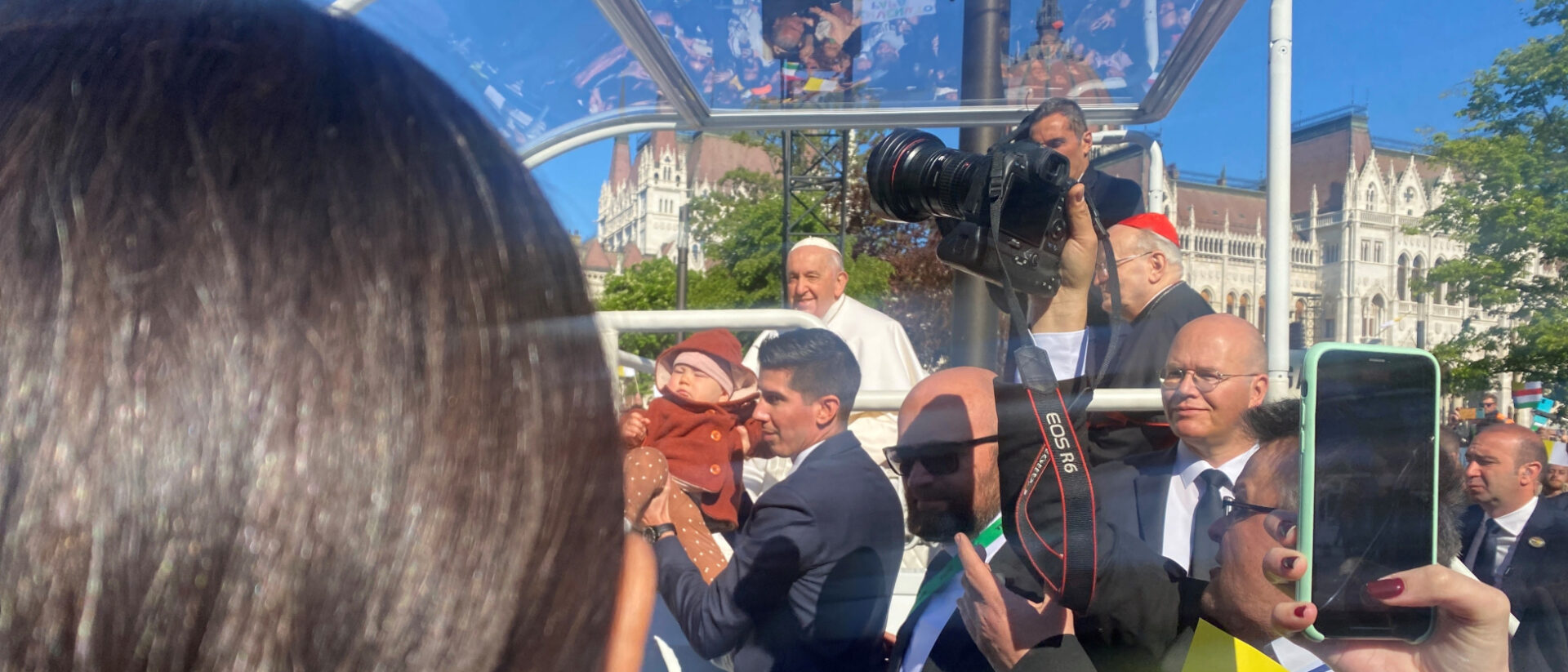 Evelin Kerékgyártó vier Monate alte Tochter (im roten Mantel) in den Händen des päpstlichen Bodyguards. Im Hintergrund lächelt der Papst im Papamobil.