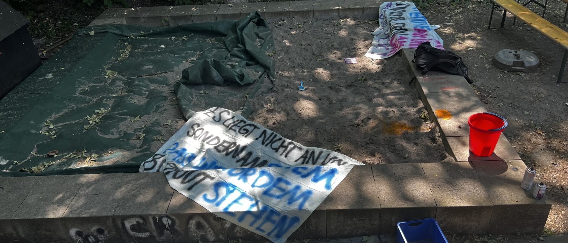 Frisch bemalte Banner trocknen an einem Sandkasten im Streikhaus.