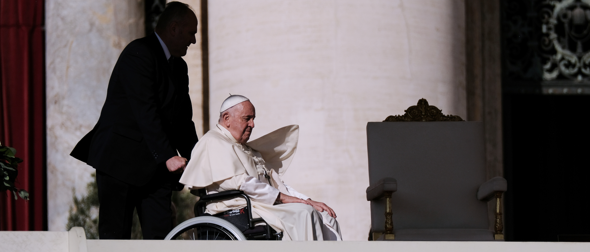 Papst Franziskus wird auf dem Rollstuhl zu seinem Sitz gefahren.
