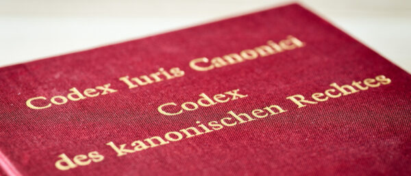 Das Kirchenrecht (Codex Iuris Canonici, Cic) hinter roten Buchdeckeln.