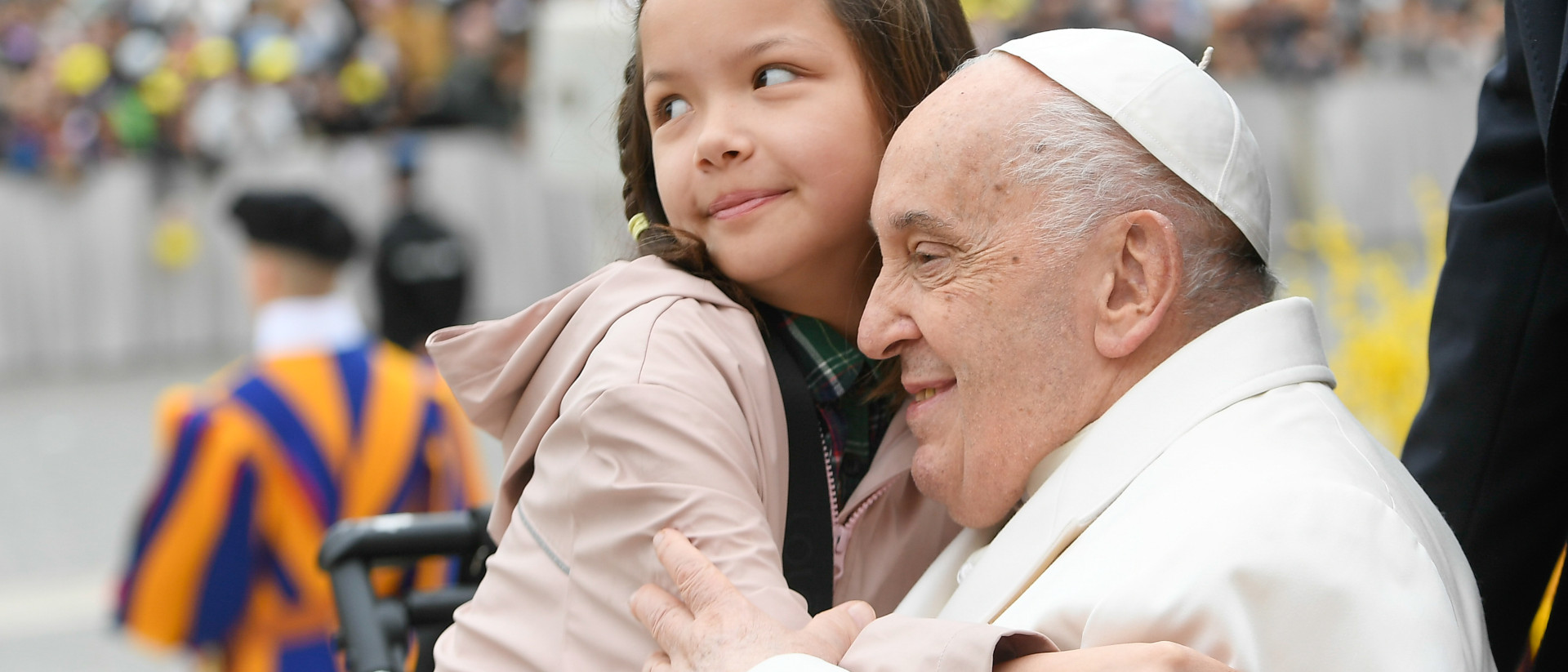Papst Franziskus wird von einem Mädchen umarmt am Ende der Generalaudienz am 3. April 2024 auf dem Petersplatz im Vatikan.