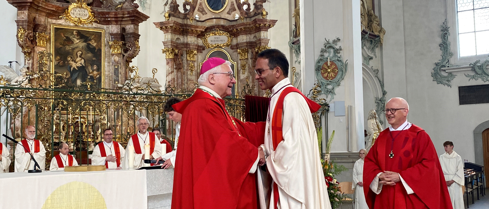 Bischof Markus Büchel (l.) gratuliert dem neuen Domherrn Mathai Ottapally, rechts Domdekan Guido Scherrer.