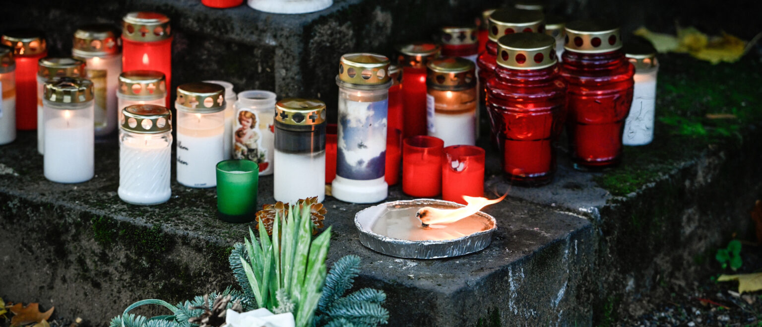 Grablichter und ein Grabgesteck stehen in der Dämmerung auf einem Friedhof. | Julia Steinbrecht/KNA