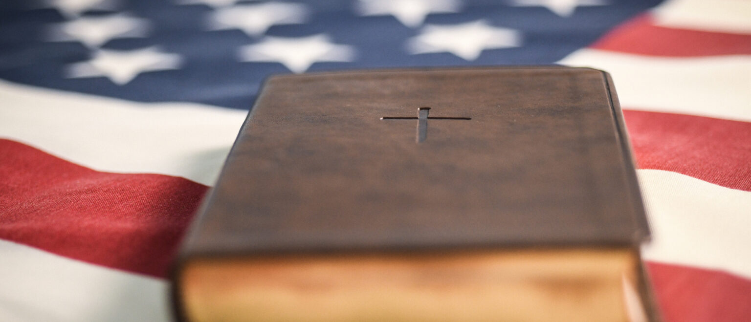Eine englischsprachige Bibel liegt auf einer US-amerikanischen Fahne. | Julia Steinbrecht/KNA