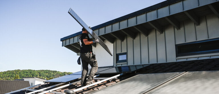 Ein Dachdecker installiert Solarpanele (l.) auf dem Dach eines Wohnhauses. | Julia Steinbrecht/KNA