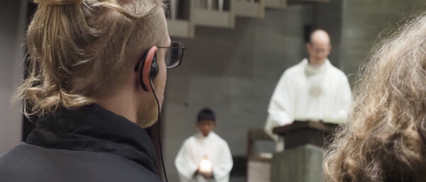 Während Pfarrer Philipp Ottiger den Gottesdienst in Muttenz leitet, hören die Teilnehmerinnen und Teilnehmer über einen Knopf im Ohr Erklärungen zu den liturgischen Handlungen und Inhalten. | Boris Burkhardt