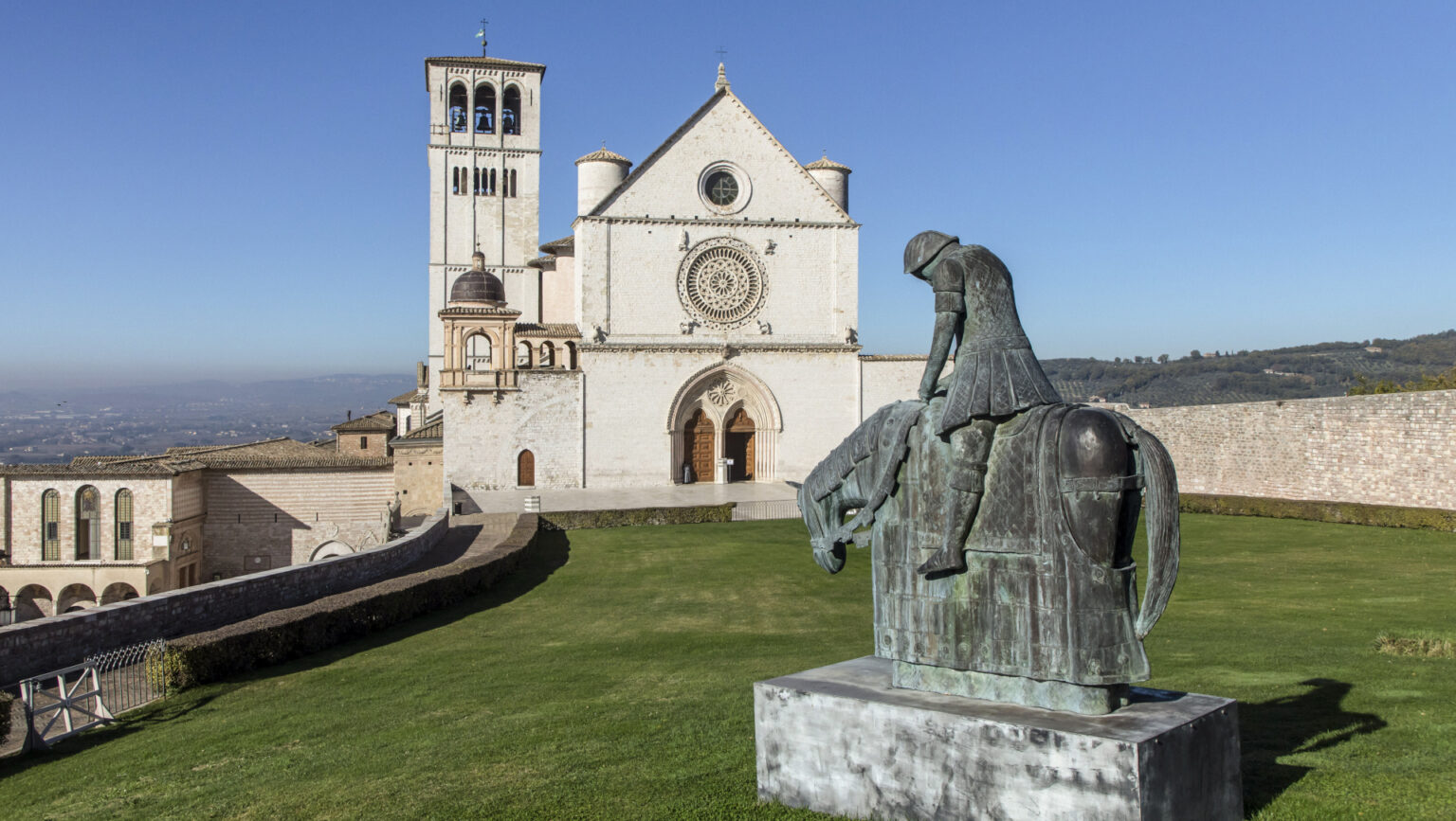 Die Basilika San Francesco in Assisi, im Vordergrund die Statue des heiligen Franziskus auf dem Pferd, 2020. | Stefano Dal Pozzolo/Romano Sicil
