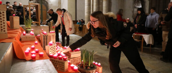 Gläubige stellen brennende Kerzen auf ein orangefarbenes Tuch vor dem Altar in der Kathedrale von Sitten. | Bernard Hallet