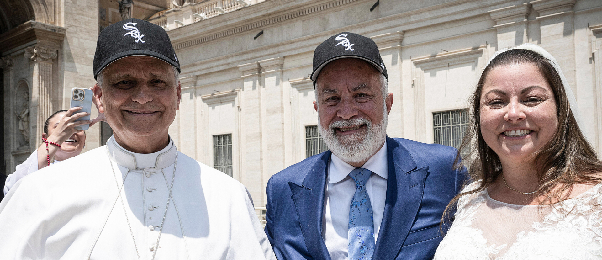 Papst Leo XIV. mit einem Brautpaar, beide Männer tragen die Kappe der Baseballmannschaft Chicago White Sox, am 11. Juni 2025 bei der Generalaudienz auf dem Petersplatz im Vatikan. | Vatican Media/Romano Siciliani/KNA