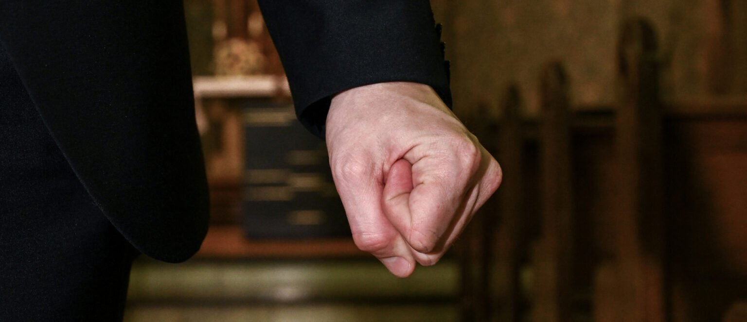 Ein Priester mit geballter Faust, Symbolbild für Missbrauch im Umfeld der Kirche | Harald Oppitz/KNA
