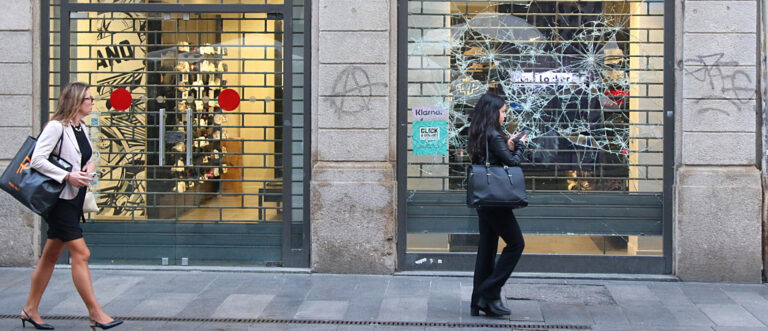 Menschen gehen an einer zertrümmerten Schaufensterscheibe vorbei, nachdem es in Mailand (Italien) im Oktober 2026 zwei Tage lang zu Ausschreitungen von Jugendlichen gekommen war. | Keystone